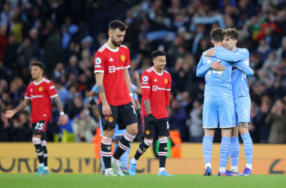 MANCHESTER, ENGLAND - MARCH 06: John Stones and Aymeric Laporte of Manchester City celebrate as Bruno Fernandes of Manchester United looks dejected after the Premier League match between Manchester City and Manchester United at Etihad Stadium on March 06, 2022 in Manchester, England. (Photo by Alex Livesey - Danehouse/Getty Images)